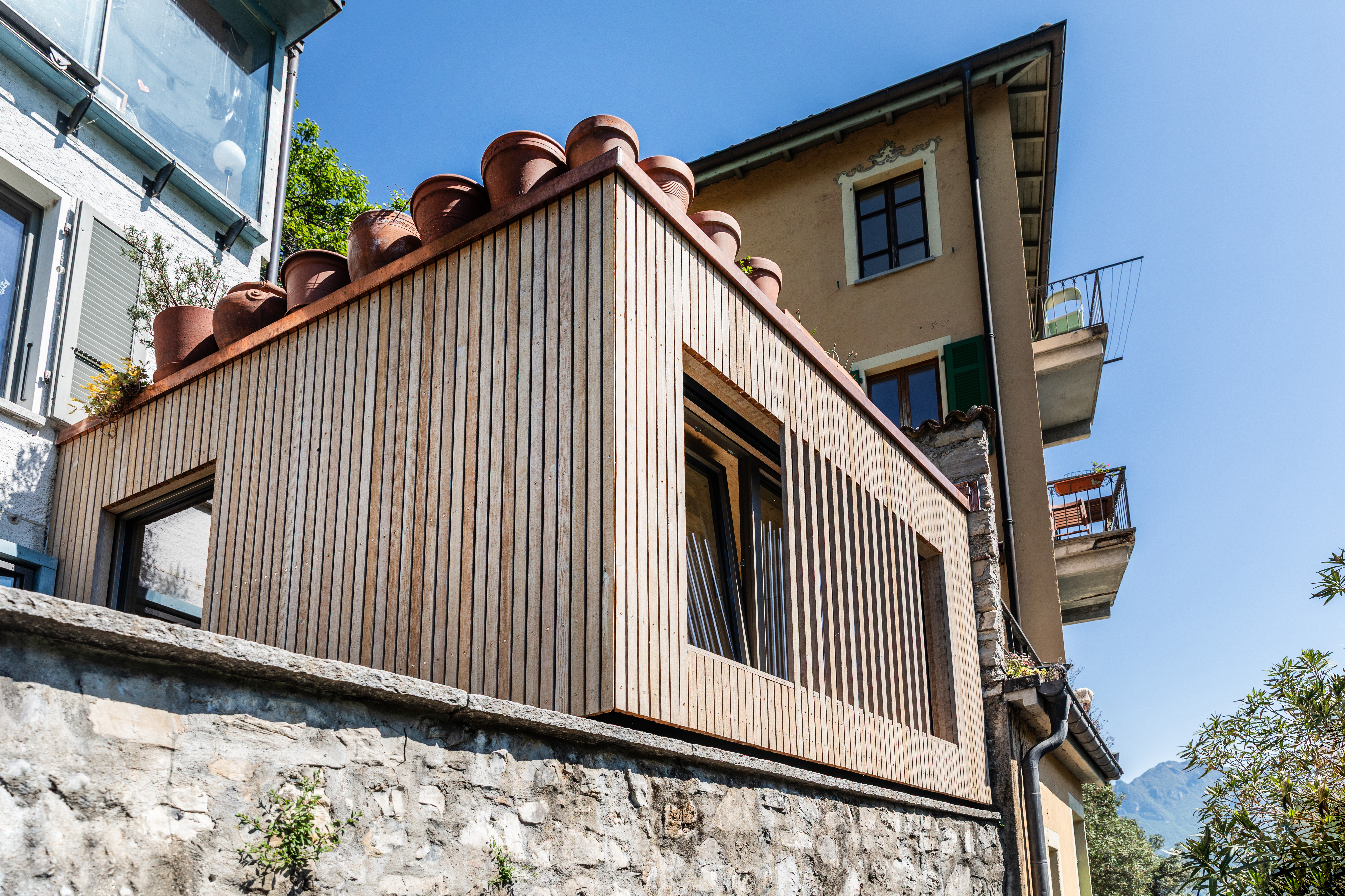 Ingrandimento in legno di una mini-casa in riva al lago
